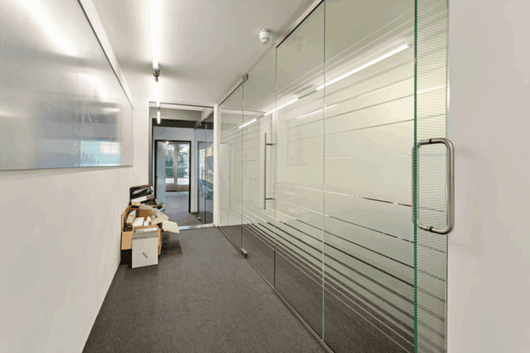 Modern kantoor met glazen schuifwanden en flexibele werkruimtes.