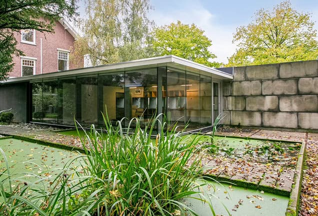 Moderne glazen kantoorruimte in groene omgeving.